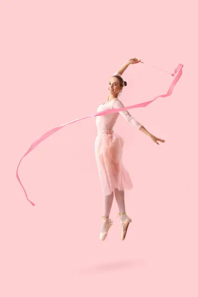 stock image Portrait of female rhythmic gymnast dancing with ribbon on pink background