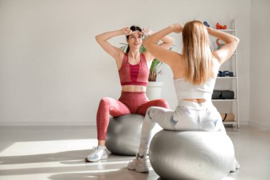 Fizyoterapistli güzel, mutlu, olgun bir kadın rehabilitasyon merkezinde vücut geliştirme egzersizi yapıyor.