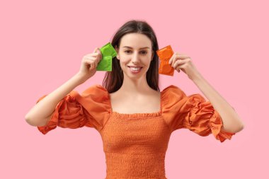 Pembe arka planda prezervatifleri olan güzel bir kadın.