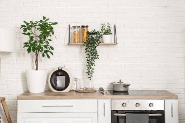 Beyaz tezgahlı ve çiçekli aydınlık mutfağın içi.