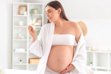 Spa salonunda çiçekli hamile bir kadın.