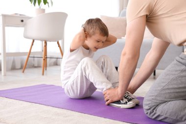 Young man and his little son doing exercises in living room