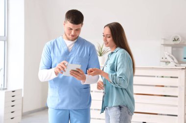 Klinikte tablet bilgisayar kullanan hasta resepsiyonist.