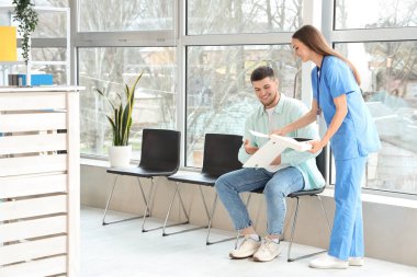 Klinikte çalışan hasta ve klasörlü kadın resepsiyonist.