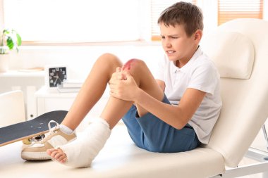 Little boy with injured leg sitting on couch in clinic