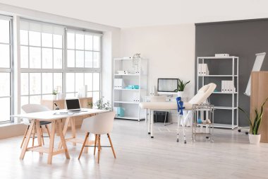 Masaları, kanepesi ve raf üniteleri olan bir tıp bürosu.