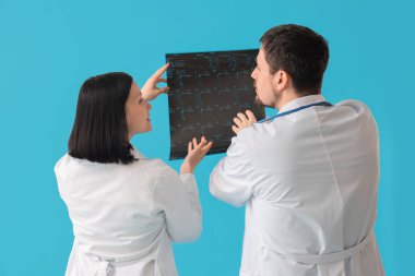 Omurganın mavi arka plandaki röntgen görüntüsü üzerinde çalışan doktorlar