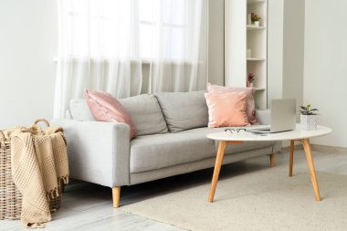 Oturma odasının iç tarafında dizüstü bilgisayarı olan rahat bir kanepe ve masa.