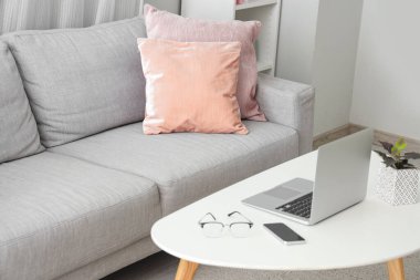 Laptoplu kahve masası ve oturma odasında rahat bir kanepe.