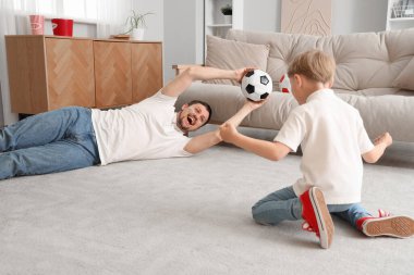 Evde futbol topu olan genç bir baba ve küçük bir oğul.