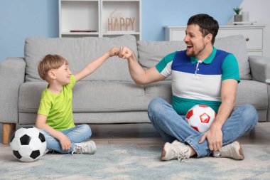 Küçük baba ve küçük oğlu evde futbol topuyla eğleniyorlar.