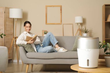 Oturma odasındaki kanepede oturan genç bayana karşı modern nemlendirici.