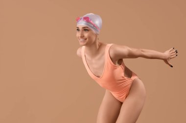 Bej arka planda poz veren mutlu genç bayan yüzücü