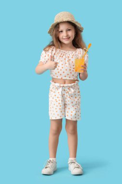Mavi arka planda bir bardak limonatası olan sevimli küçük bir kız.