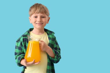 Mavi arka planda bir sürahi limonatası olan şirin bir çocuk.