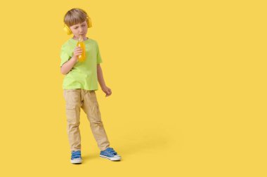 Sarı arka planda limonata şişesi olan şirin bir çocuk.