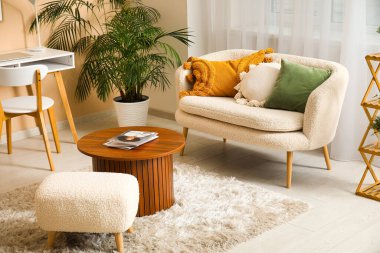 Beyaz kanepesi, sehpası, işyeri ve perdesi olan aydınlık oturma odası.