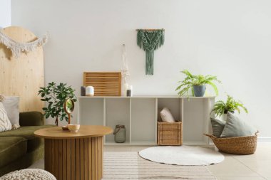 Raf ünitesi ve duvar halısıyla aydınlık oturma odasının içinde.