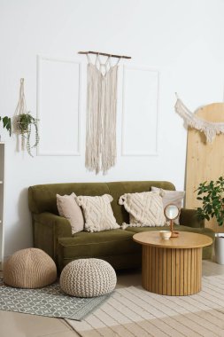 Interior of light living room with green sofa and wall tapestry