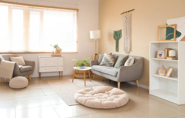 Interior of cozy living room with sofa, drawers and wall tapestries