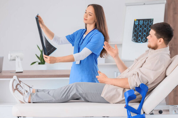 Женщина-врач с рентгеновским снимком позвоночника и молодой человек в больнице