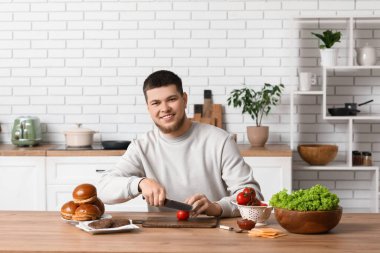 Genç adam mutfakta domates doğruyor.