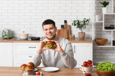 Mutfakta lezzetli burgeri olan genç bir adam.