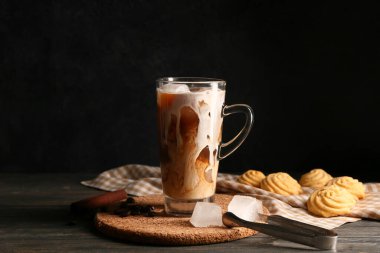 Kahve çekirdekli buzlu latte ve ahşap masada tatlı kurabiyeler.
