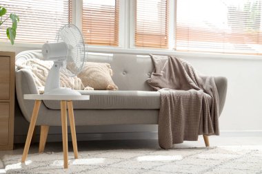 Oturma odasındaki masada elektrikli vantilatör var.