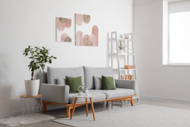 Rahat kanepesi, raf ünitesi, sehpası ve beyaz duvarlı resimleri olan şık bir oturma odası.