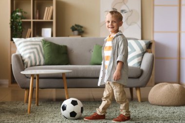 Evde futbol topuyla oynayan küçük bir çocuk.
