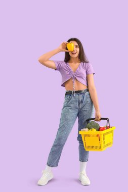 Dolu biberli ve leylak kaplama alışveriş sepetli genç bir kadın.