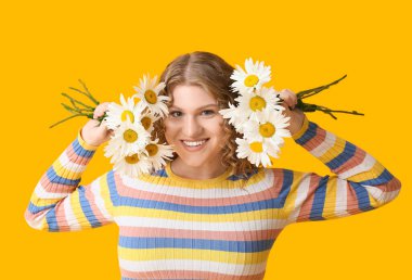 Sarı arka planda papatya çiçekleri olan güzel genç bir kadın.