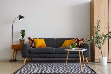 Modern oturma odasının içinde siyah kanepe, masa ve lamba var.