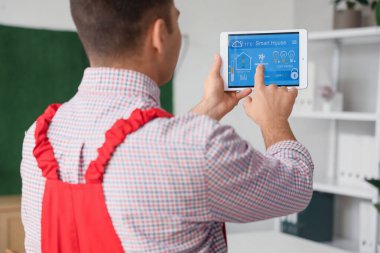 Ofiste alarm sistemi yüklü tablet bilgisayar kullanan erkek işçi, kapat