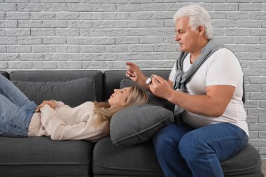 Cep saati olan bir erkek psikolog ofisinde yalancı bir kadını hipnotize ediyor.