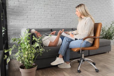 Ofiste hipnoz sırasında olgun bir adamla çalışan kadın psikolog.