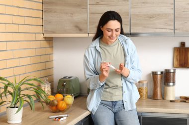 Mutfakta tükenmez kalem kullanan şeker hastası genç bir kadın.