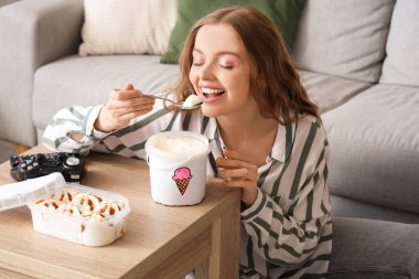 Evde dondurma yiyen genç bir kadın.