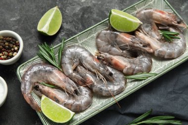 Taze çiğ karides, kireç ve gri arka planda biberiye.