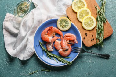 Lezzetli haşlanmış karides, yeşil arka planda limon ve biberiye.