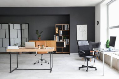 Masaları ve raf ünitesi olan modern ofisin içi