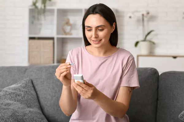 stock image Diabetic young woman with glucose test strip and glucometer on sofa at home