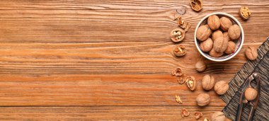 Ahşap zemin üzerinde ceviz ve fındık kıracağı olan bir kase metin ve üst görünüm için yer.