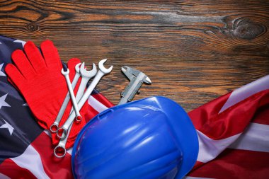 Sert şapka, aletler ve ahşap arka planda Amerikan bayrağı. İşçi Bayramı kutlamaları