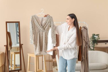 Stüdyoda askıda giysileri olan mutlu bir kadın stilist.