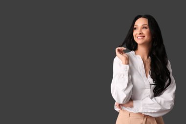 Siyah arka planda beyaz bluzlu siyah dalgalı saçlı güzel bir kadın.