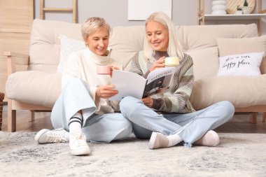 Evde elinde çay fincanları olan olgun kadınlar.