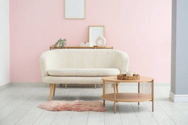 Oturma odasında halı ve kahve masası olan yumuşak beyaz bir kanepe.