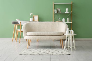 Oturma odasında raf ünitesi ve halı olan rahat beyaz bir kanepe.